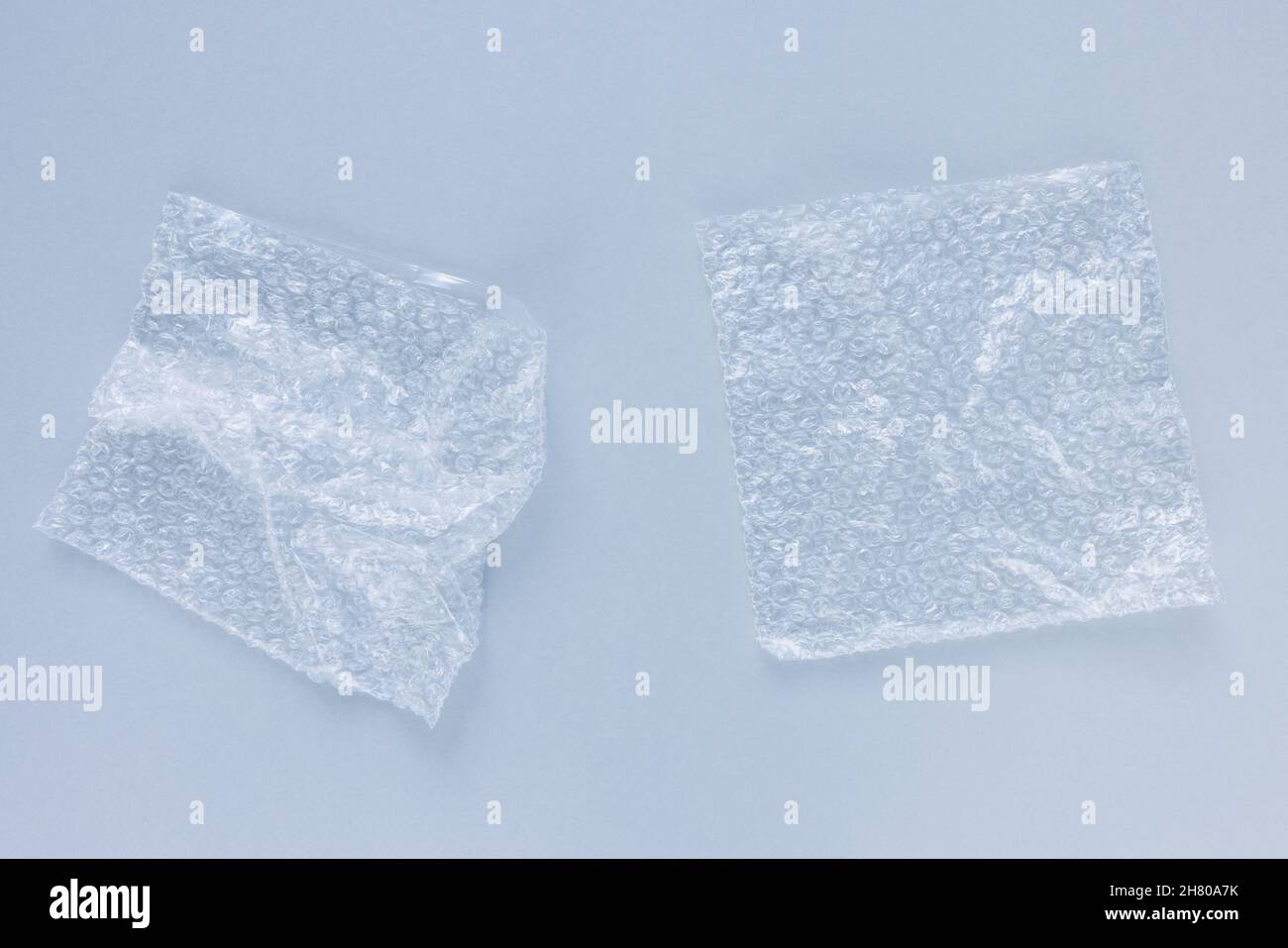 Bubble wrap bags for packaging on light blue background. Closeup, texture background, plastic pollution concept Stock Photo