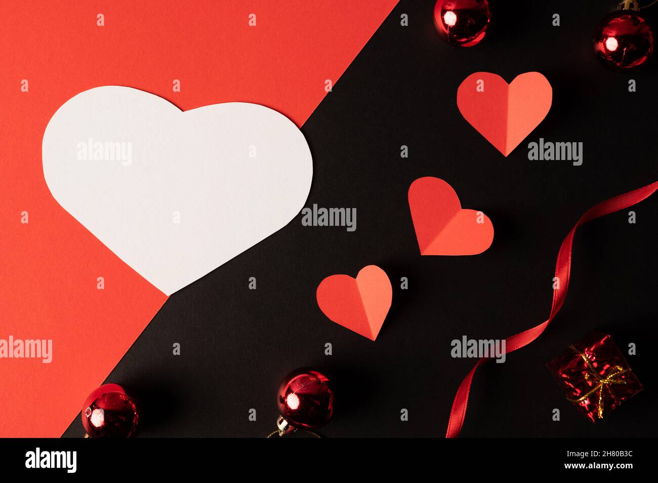 White hearts and red hearts made of paper are placed on a black ...