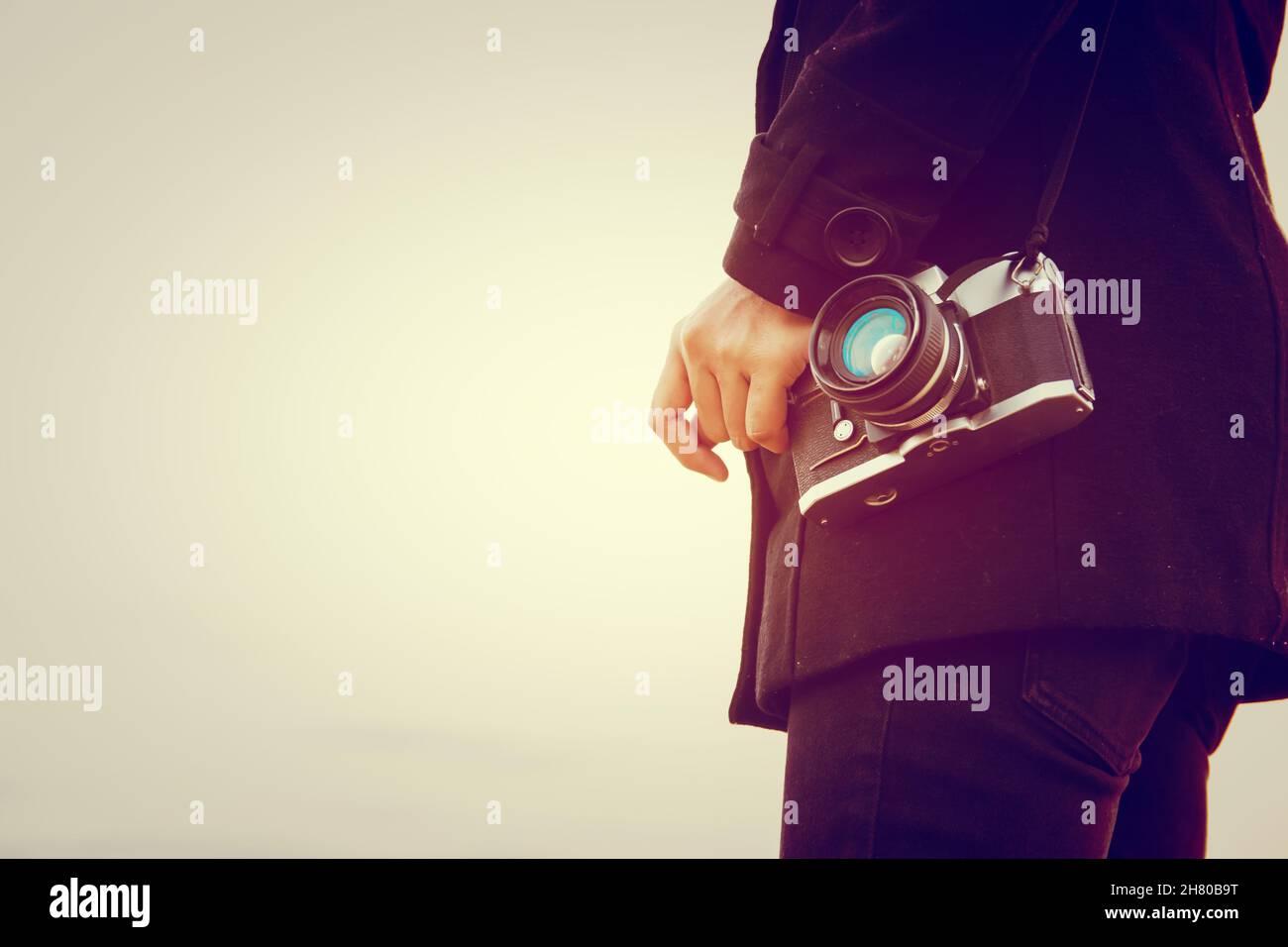 Young woman wearing black coat standing carry retro camera Stock Photo