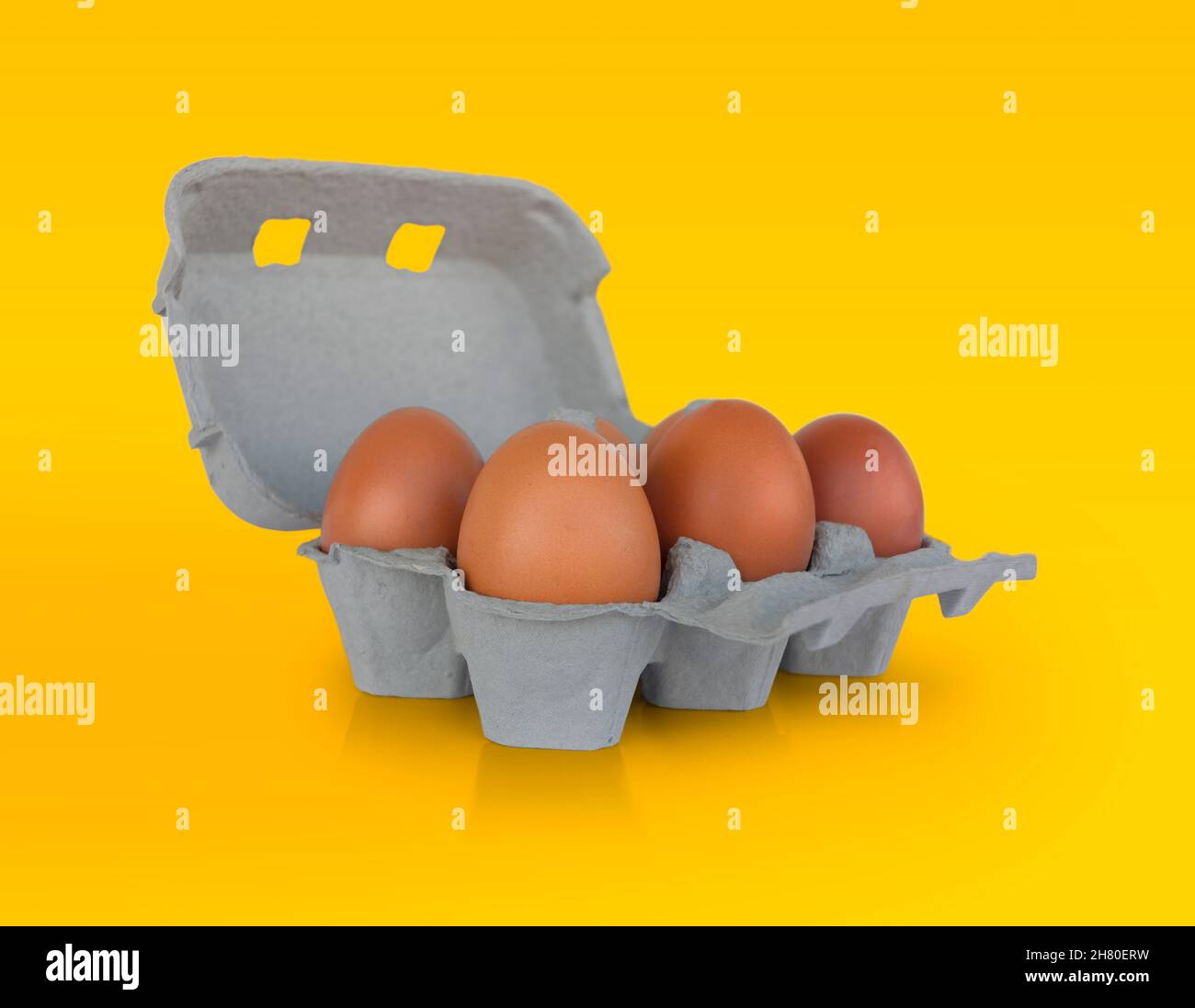 Six Brown eggs on cardboard box isolated on yellow background Stock Photo