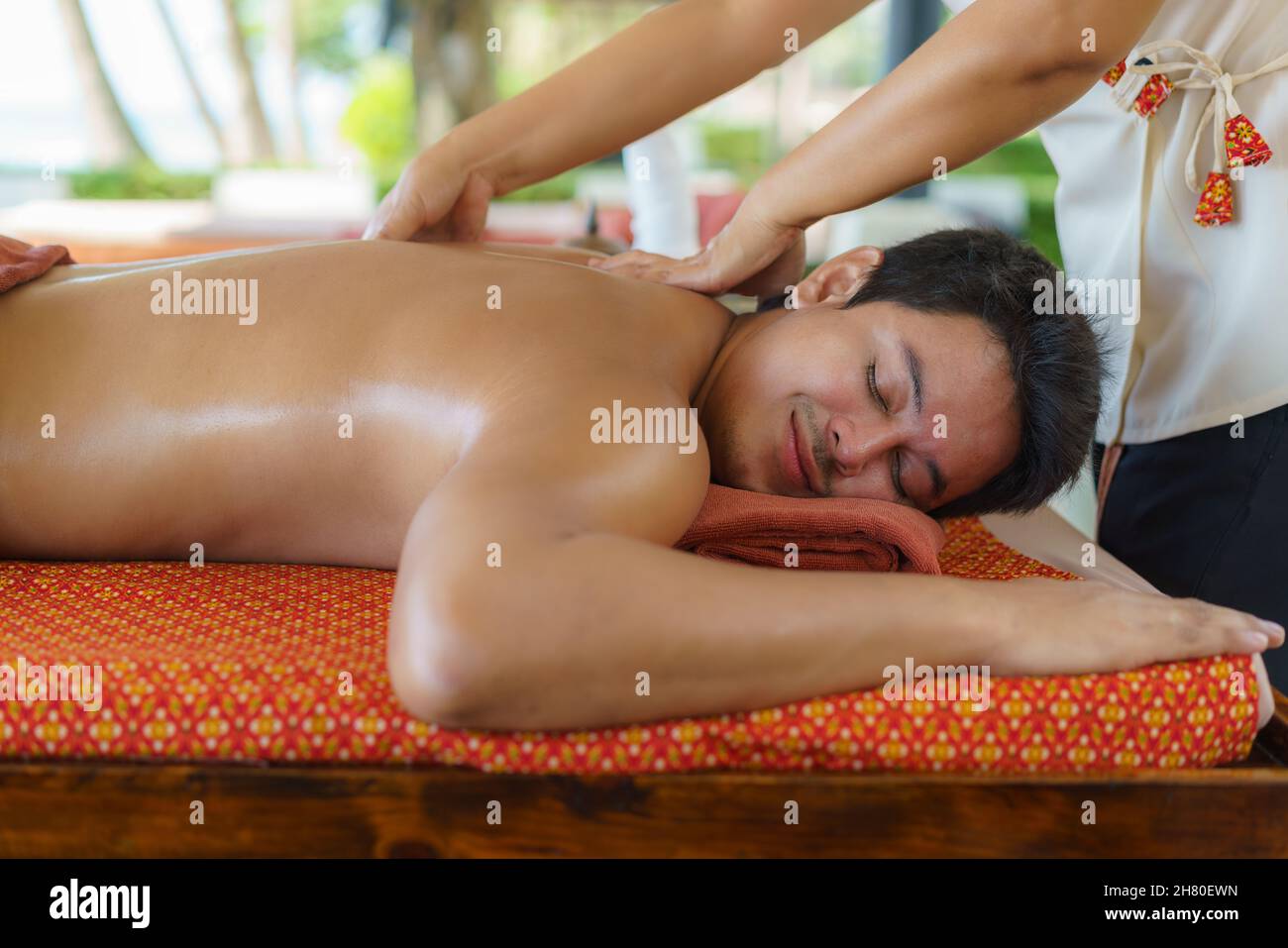 Asian man in beach spa salon getting oil massage near beach and looking happy in Thailand. Spa, resort, beauty and health concept. Stock Photo