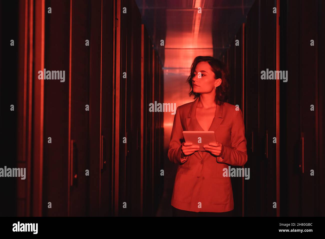 engineer with digital tablet looking at servers in data center with neon light Stock Photo