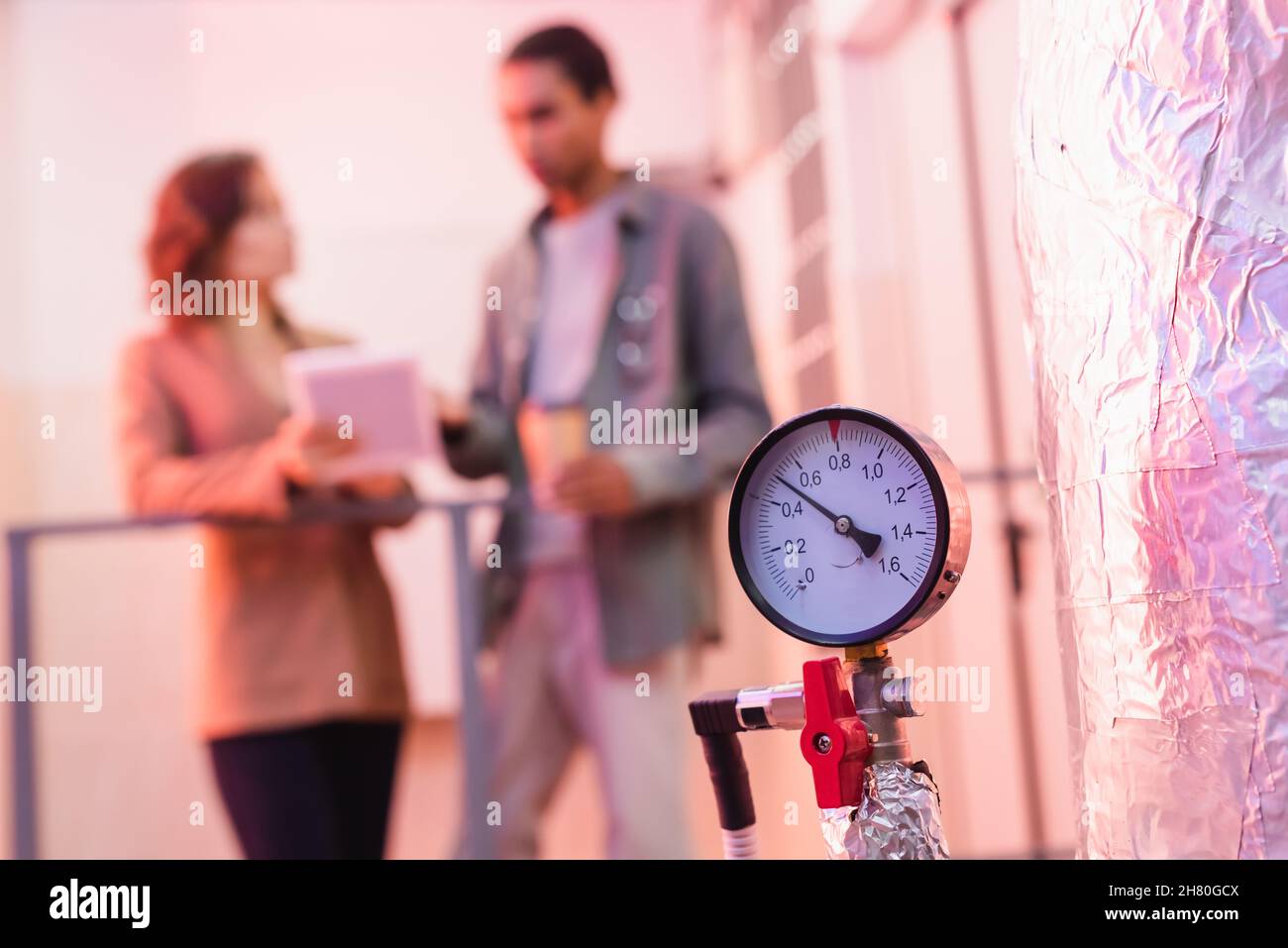 selective focus of manometer of data center cooling system near blurred interracial engineers Stock Photo