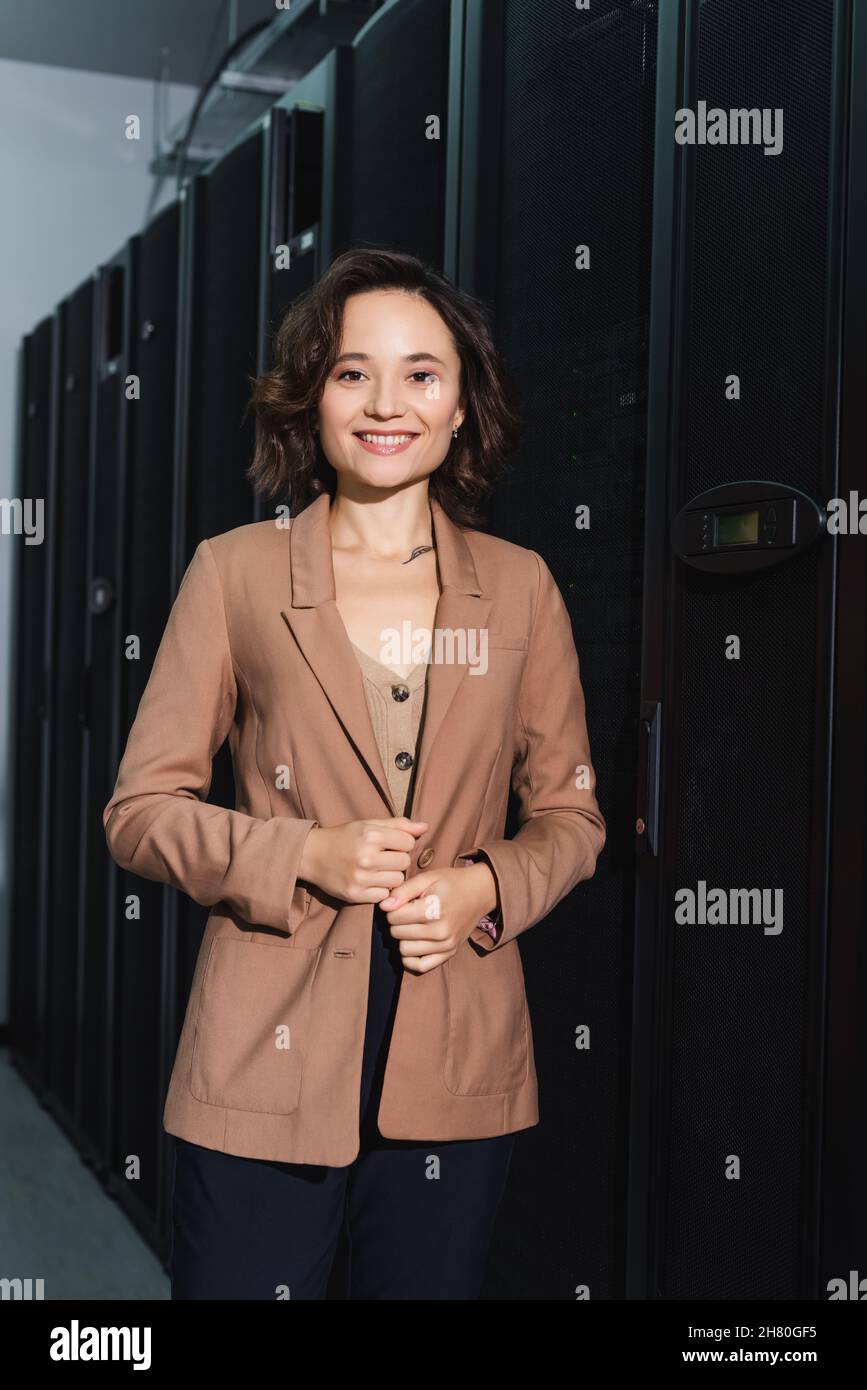 cheerful engineer smiling at camera while standing in data center Stock Photo