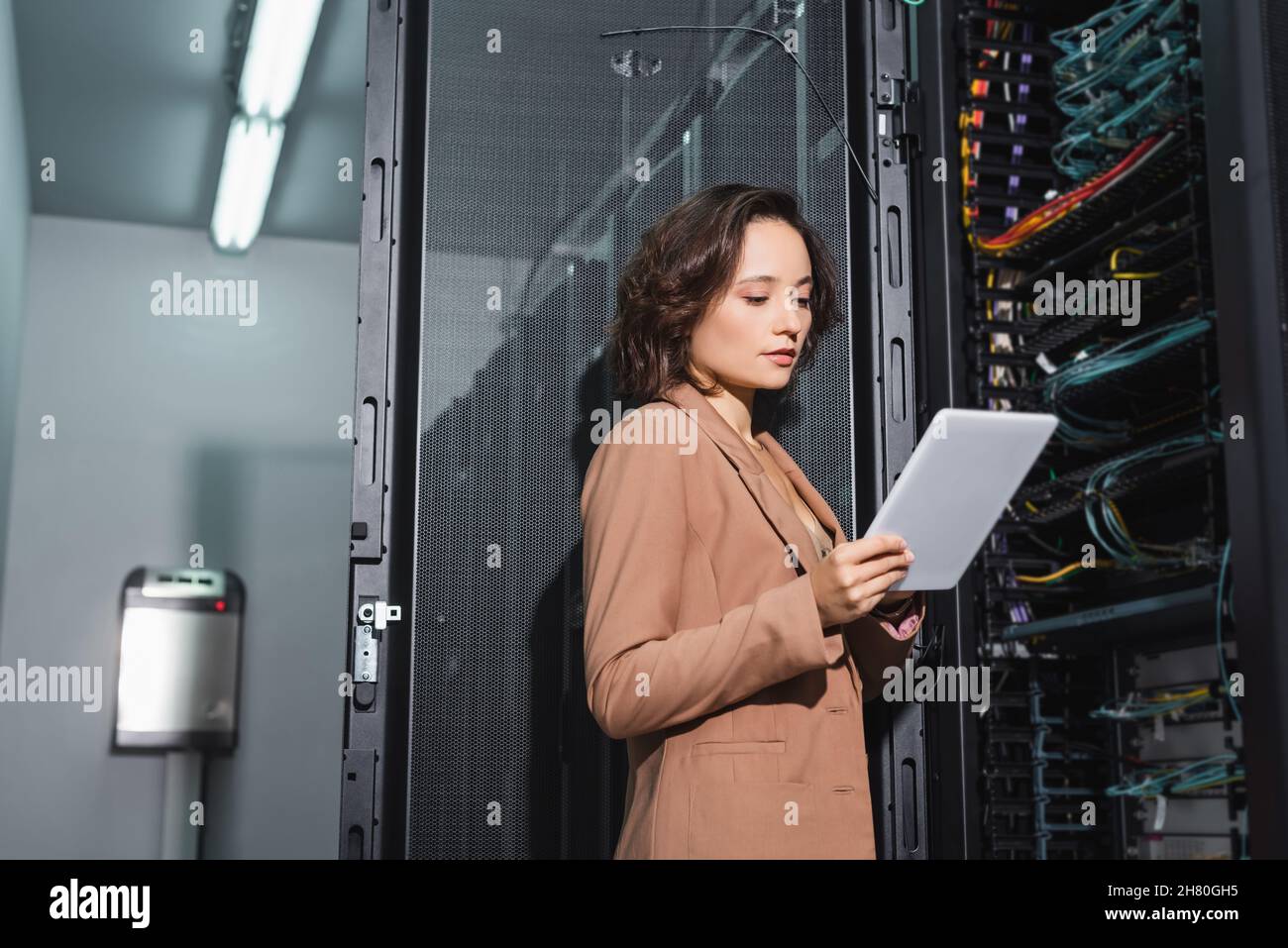 engineer looking at digital tablet while standing near open server in data center Stock Photo
