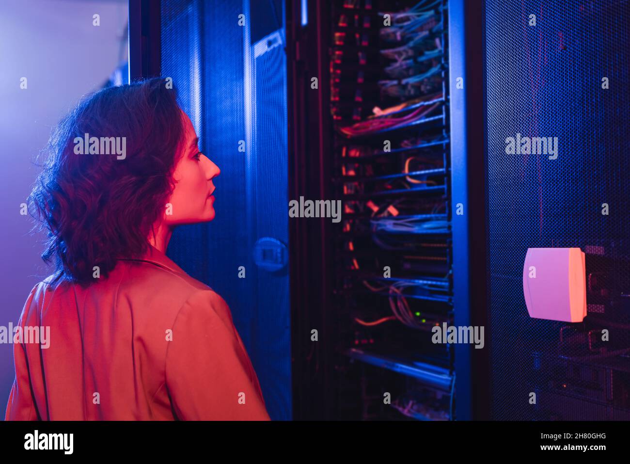 engineer checking server while working in data center in neon light Stock Photo