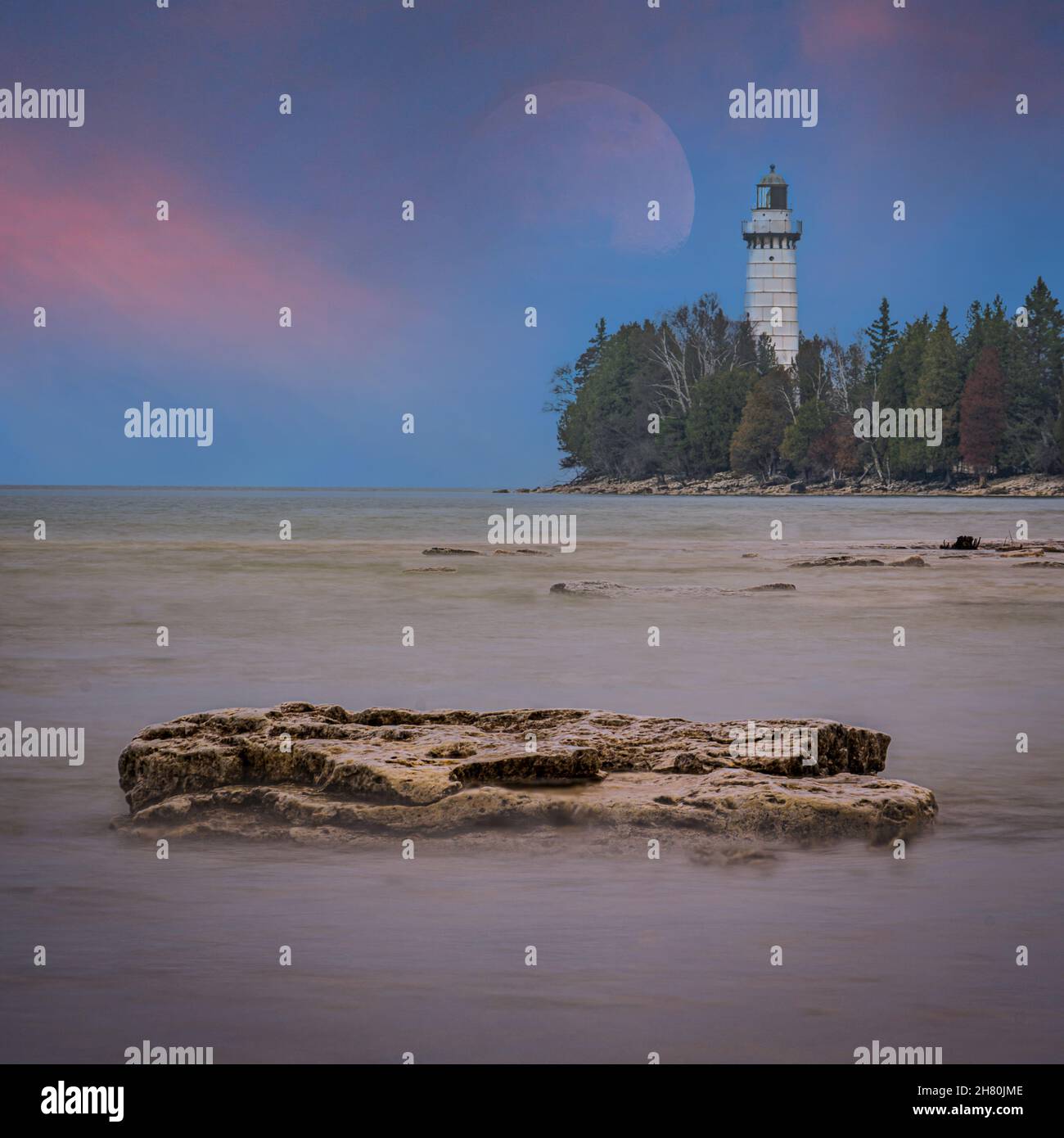 This is Cana Island with its often photographed lighthouse on a summer evening with the full moonrise in the background. Near Baileys Harbor Wisconsin Stock Photo