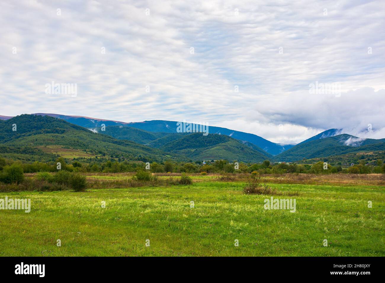 rural field in mountains at dawn. cloudy early autumn weather Stock Photo