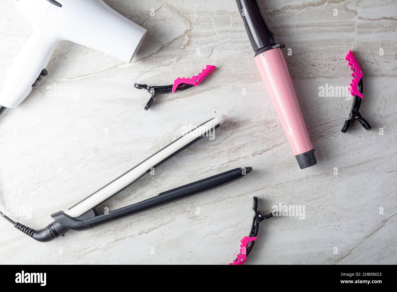 A collection of household tools used for DIY hairdo at home or in salon. The set includes curling and straightening wands, hair dryer and sectioning c Stock Photo