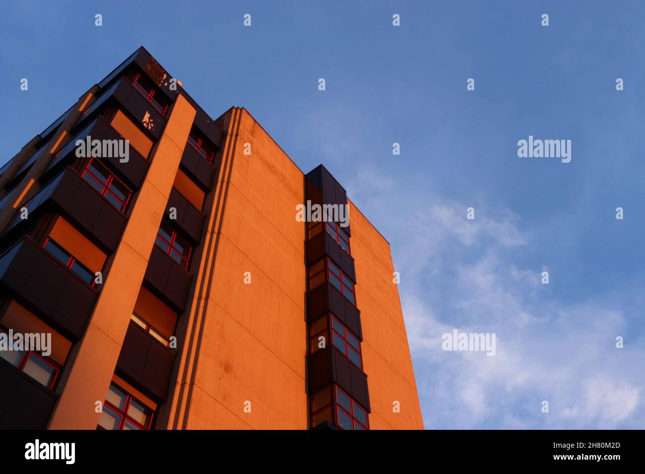 Low angle view of a modern brown building facade under a blue clear sky ...