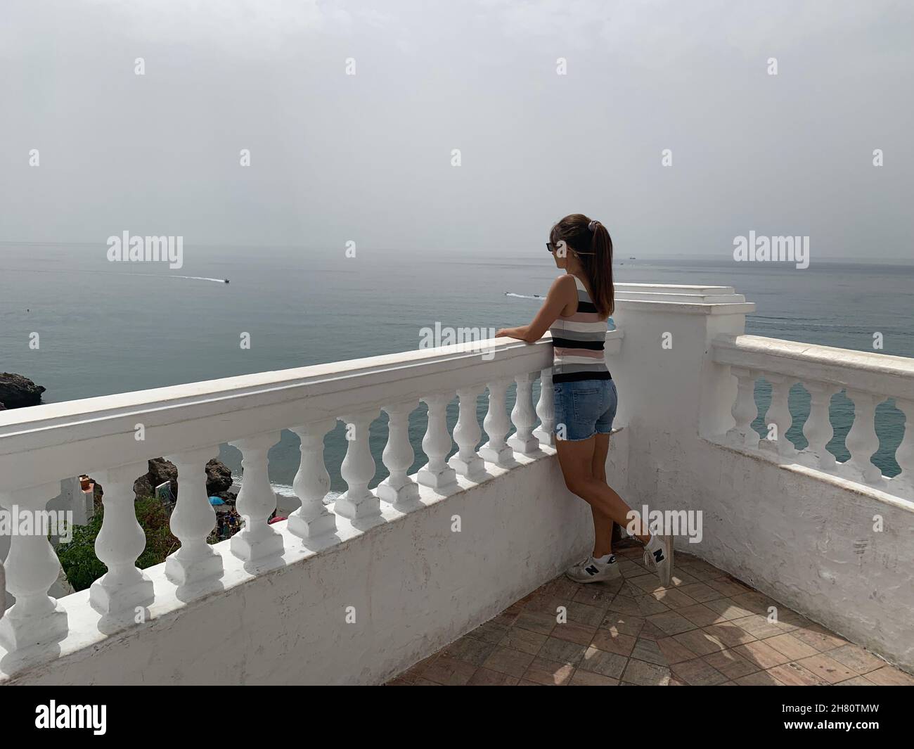Girl looking at the blue sea on her holiday the Balcón de Europa is that beautiful viewpoint located in the center of Nerja, Malaga, Spain Stock Photo
