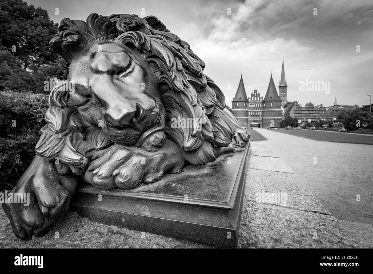 Statue Of Sleeping Lion ( 1823, Attributed to Christian Daniel Rauch) near Holsten Gate in Lubeck, Germany. Black and white photography Stock Photo