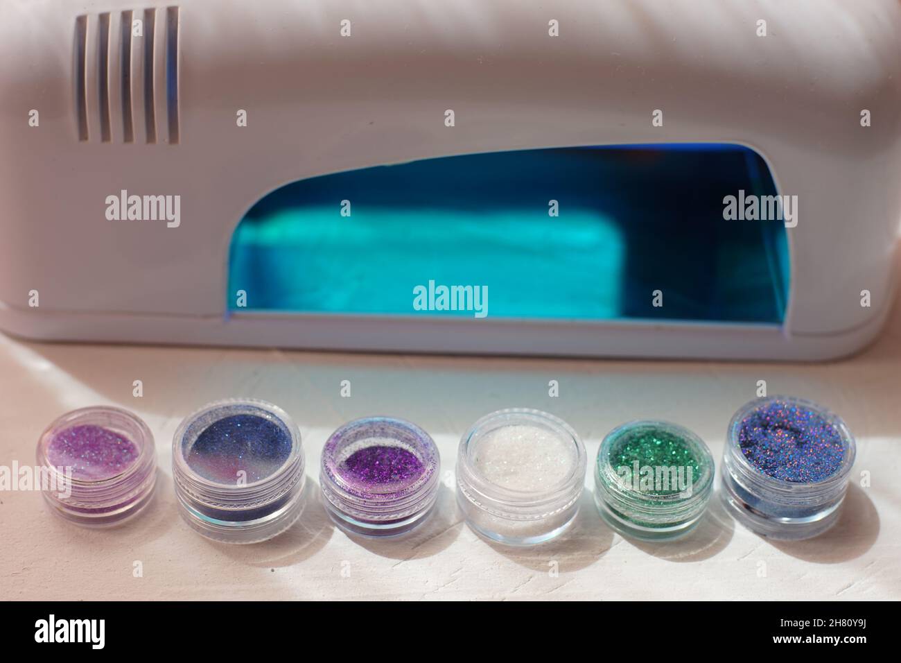 sequins for manicure and uv lamp on a white table. Stock Photo