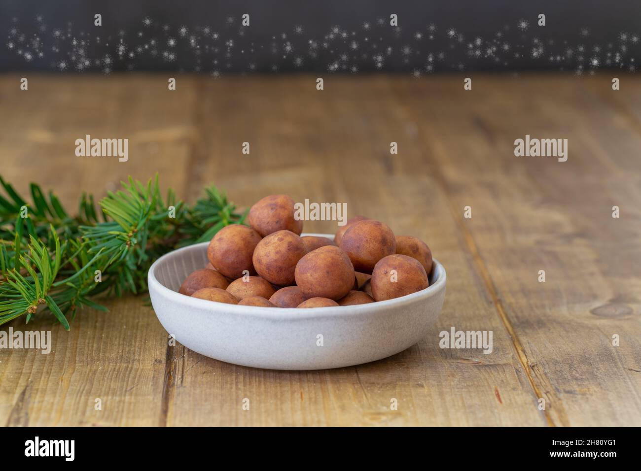 Close-up of a portion of marzipan potatoes in a little bowl on a wooden table with focus in foreground Stock Photo