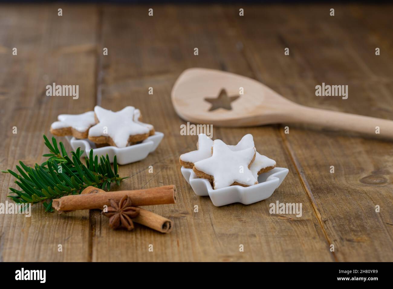 close-up of cinnamon stars as christmas cookies in a little white bowl on a wooden table, focus on foreground Stock Photo