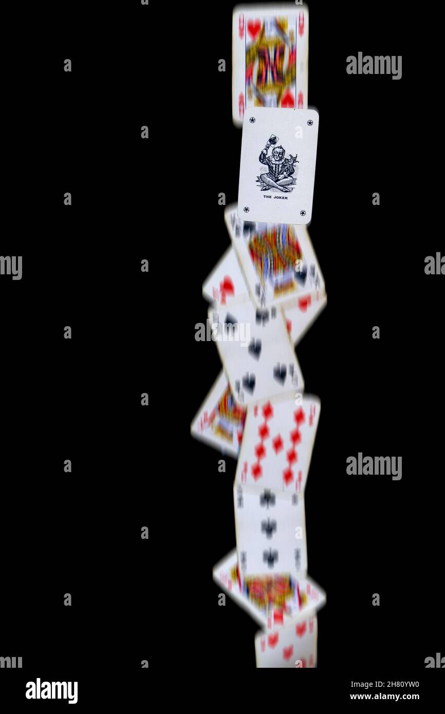 A line of playing cards fall against a black background, with the joker frozen to show it is different to the other cards. Portrait orientation. Stock Photo