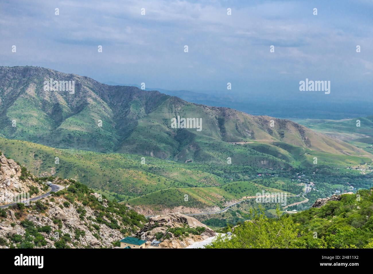 Panorama of Zarafshan mountains in eastern Uzbekistan. Mountains are part of Gissar ridge. Winding road and small village are visible Stock Photo