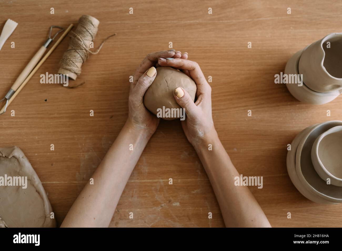 The stage of creating a pot from clay. Female hands making a hole in a piece of clay. craft work and creative craft concept. Stock Photo