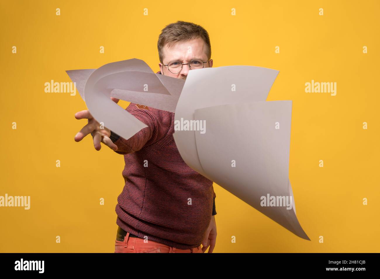 Man in stress and anger throws a stack of white paper forward. Bad working day. Psychological concept.  Stock Photo