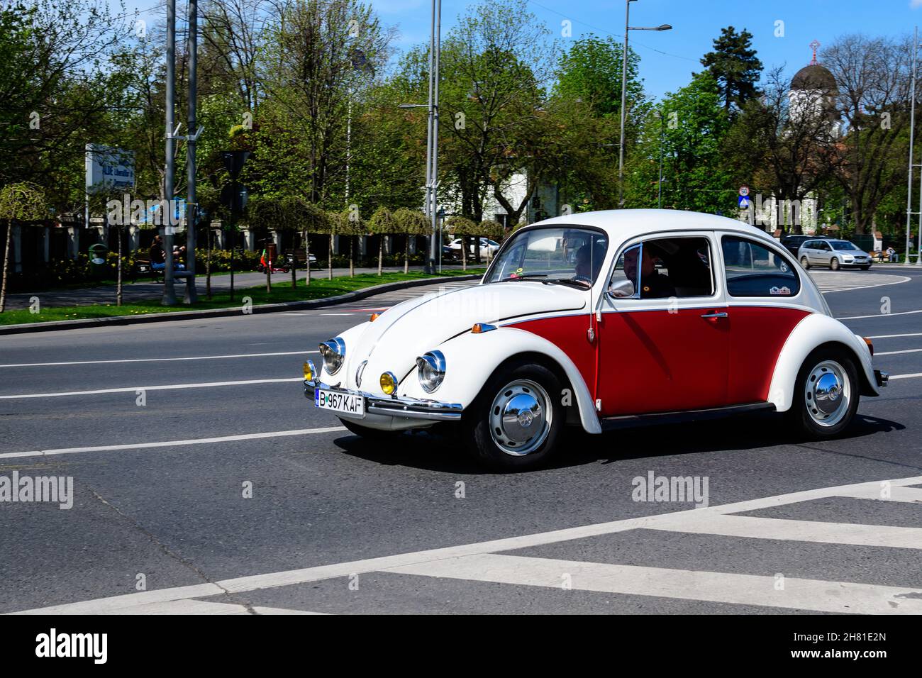 Bucharest, Romania, 24 April 2021 Old retro white and vivid red Volkswagen Beetle classic car in traffic in a street in a sunny spring day Stock Photo