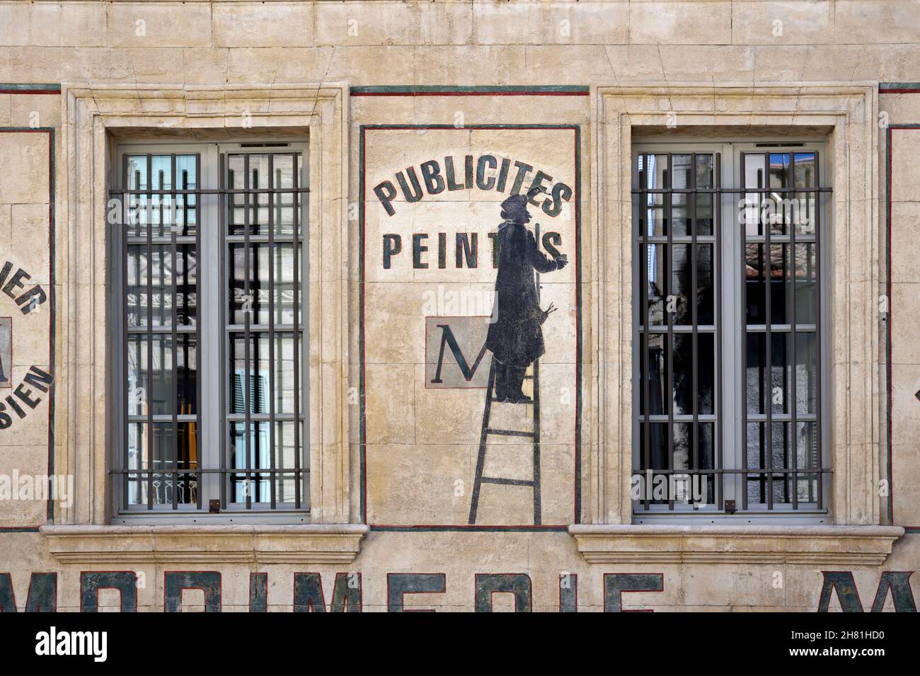 Old Painted Wall Advert or Publicity with Signwriter on Ladder on Facade of Former Printers in the Old Town Avignon Provence France Stock Photo