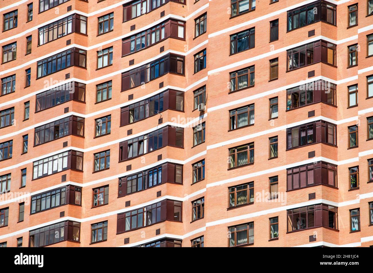 View of brick wall red contemporary apartment building with windows and balconies closeup Stock Photo