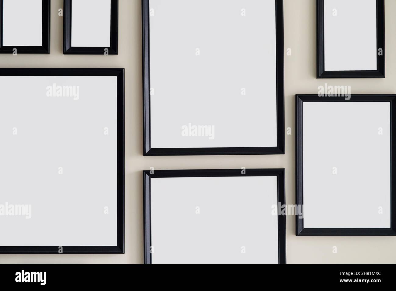 Different size framed photos hanging on the gray wall. Mockup. Stock Photo