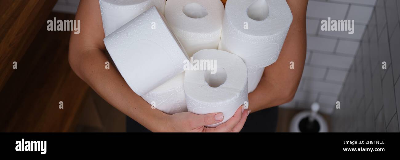 Woman sitting on toilet and holding many rolls of paper closeup Stock Photo