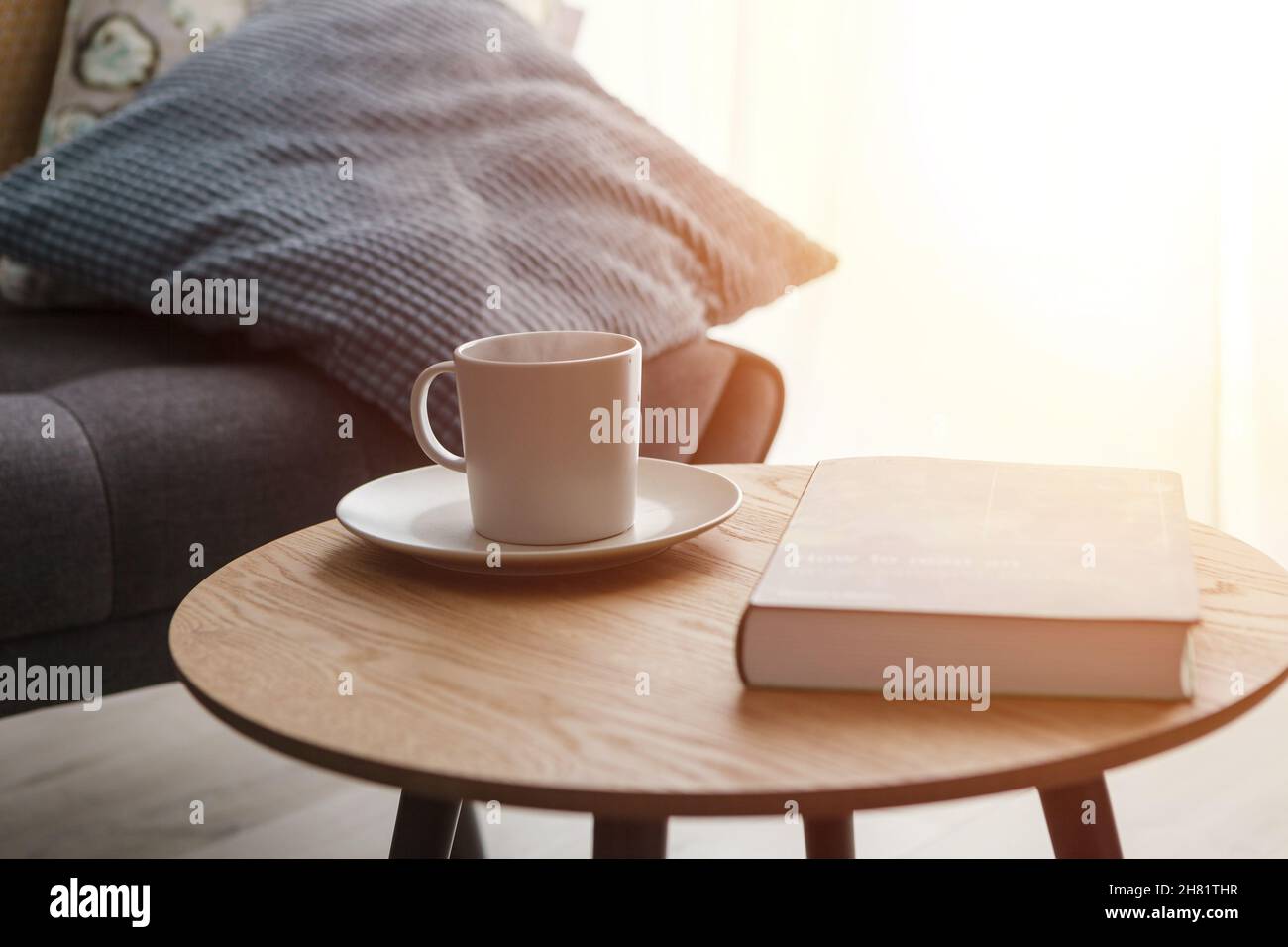 Relax at home, cup of hot tea and book on coffee table by the sofa Stock Photo