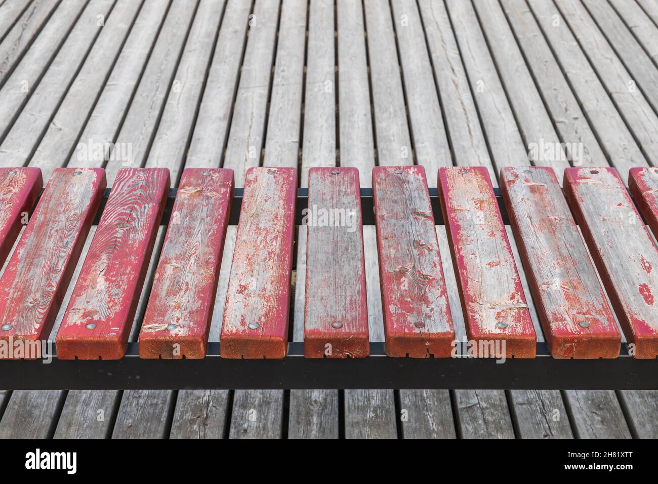 Red weathered outdoor bench with an empty promenade flooring. Abstract background photo, wooden boards perspective Stock Photo