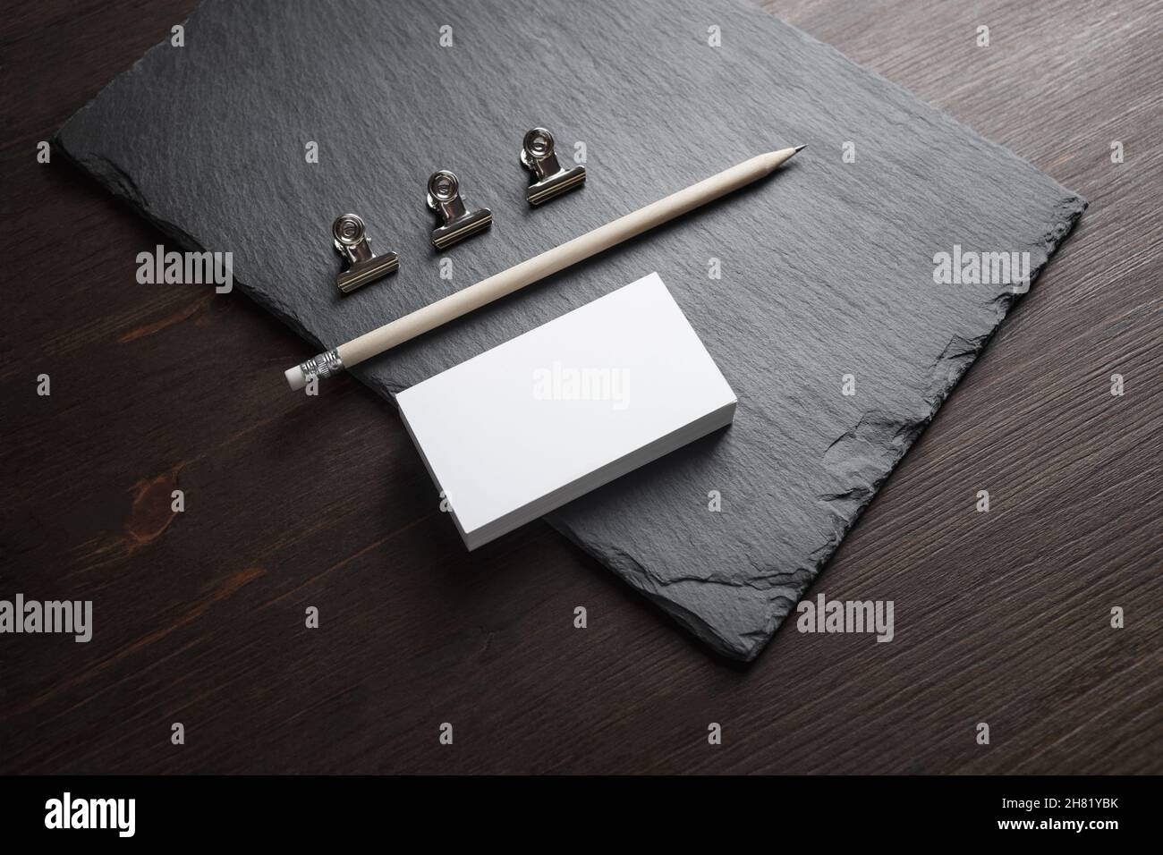 Photo of blank business cards, pencil and metal clamps on stone board background. Template for ID. Stock Photo