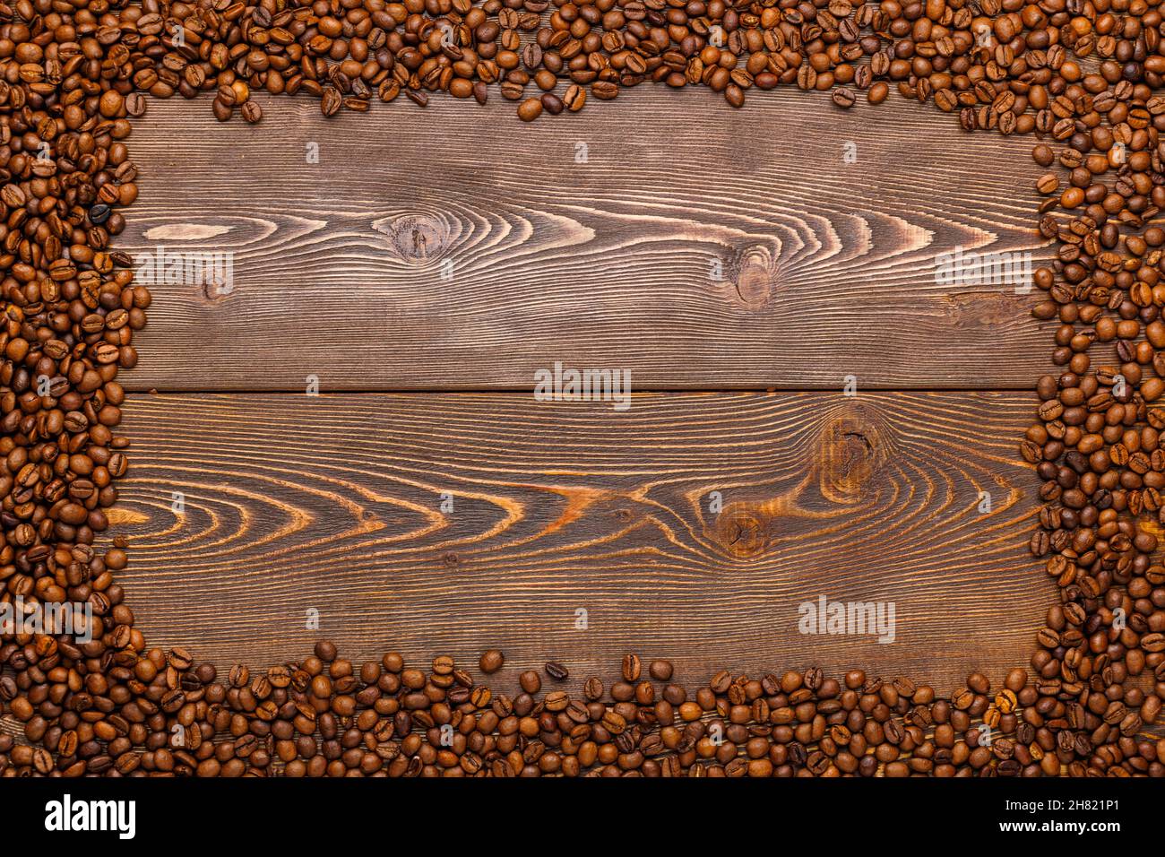 rectangular frame of many roasted coffee beans on brown wooden surface Stock Photo