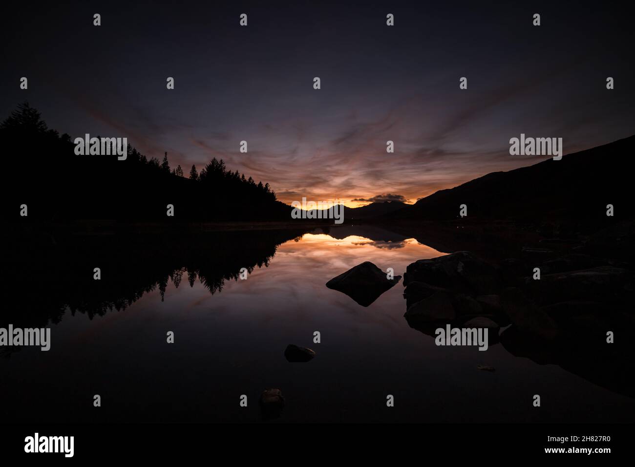 Reflection of colourful sky at dusk in Llyn Mymbyr, Snowdonia, North Wales Stock Photo