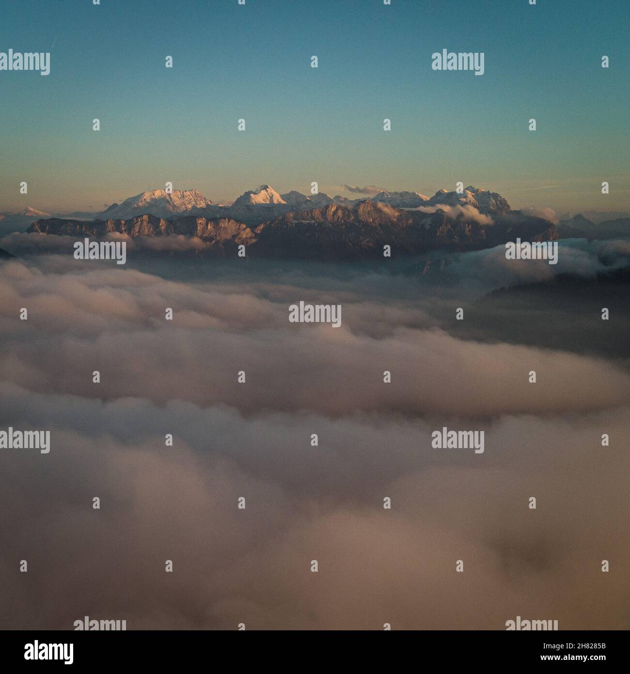 Foggy view with snowy rocky mountains on the horizon under a blue sky ...