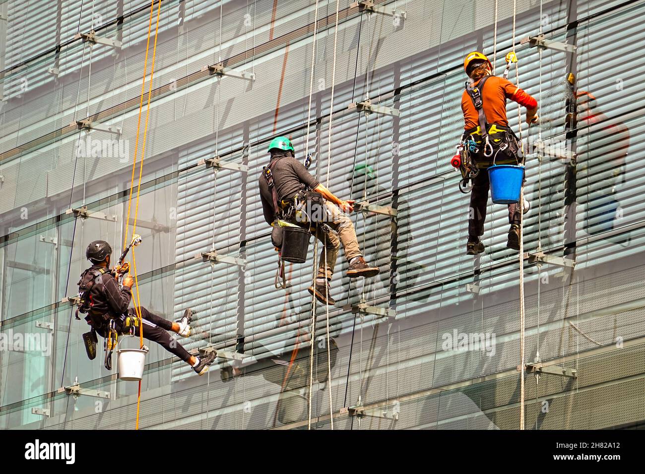 Luxembourg City, Luxembourg, September 2, 2020: Professional building  cleaners equipped with climbing gear cleaning windows on the outside of a moder Stock Photo
