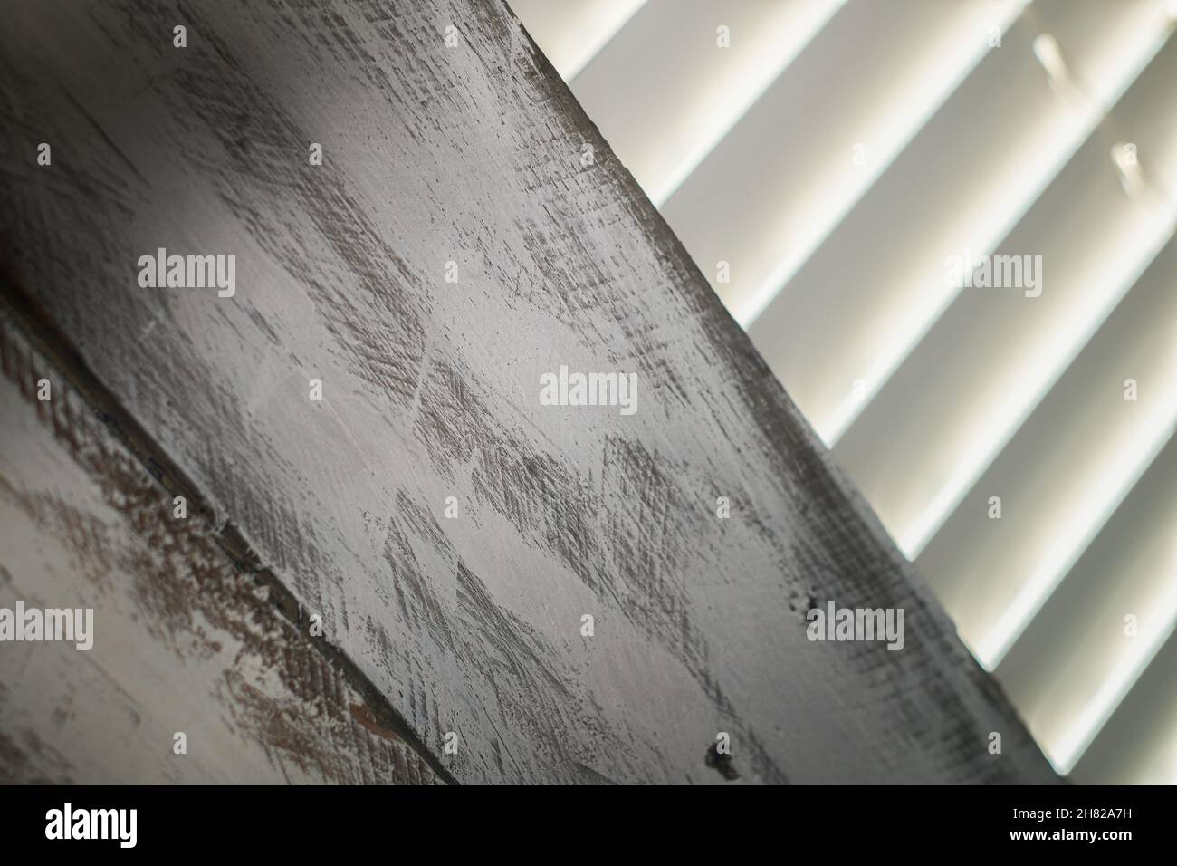 A partially boarded window with closed Venetian blinds. Stock Photo