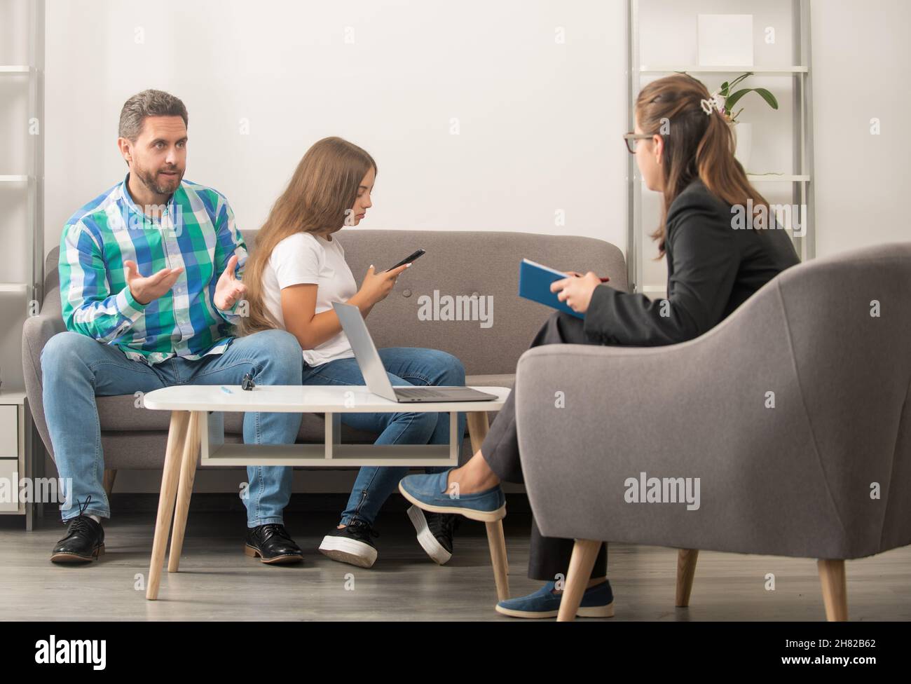 worried father talk to family psychologist about phone addicted child, therapy Stock Photo