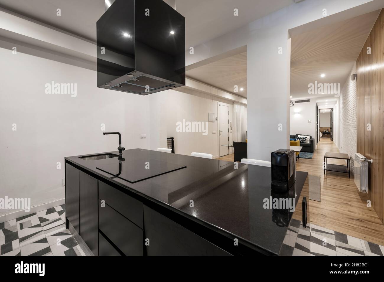 Black marble kitchen island with hob and hood in a vacation rental apartment Stock Photo
