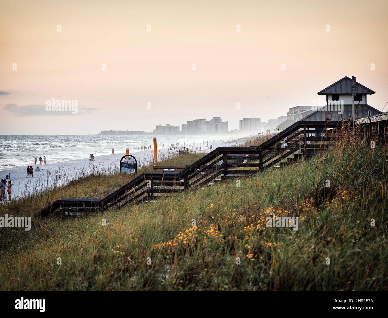 Grass covered sand dunes leading down to the beach on a windy day with high surf on Miramar Beach looking toward high rise condos Destin Florida, USA. Stock Photo