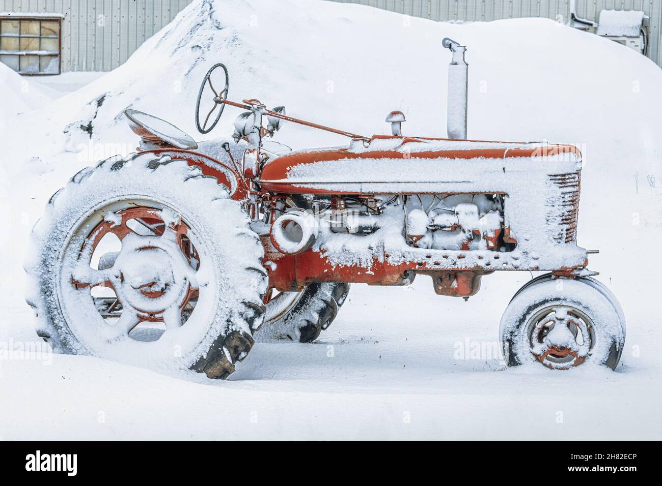 An old antique tractor covered in snow. Stock Photo