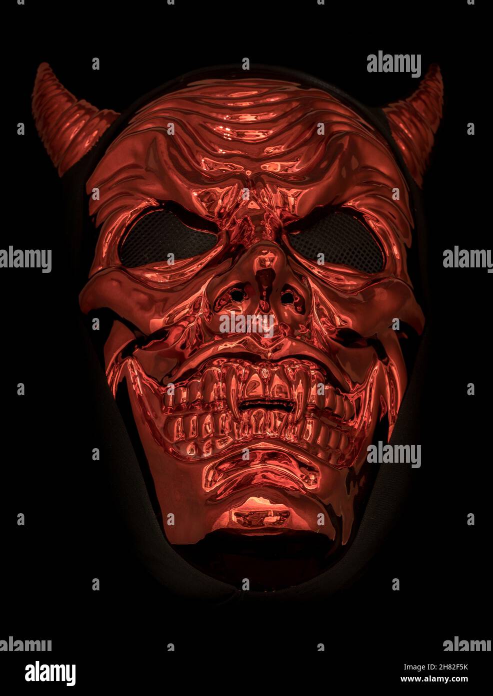 Metallic Red Devil Mask Isolated Against Black Background Stock Photo