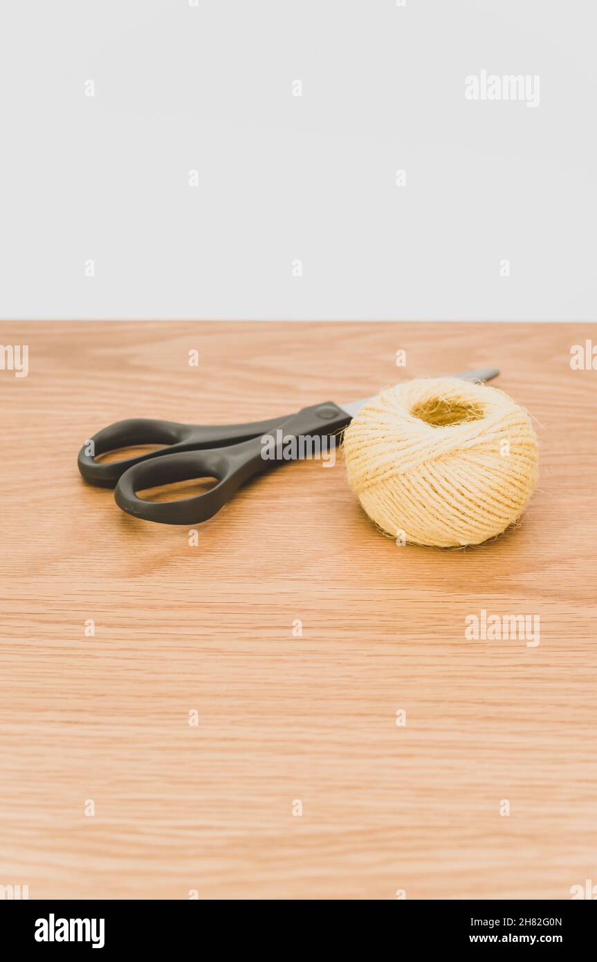 decorative rustic yellow yarn ball and scissors on a wooden tabletop ...