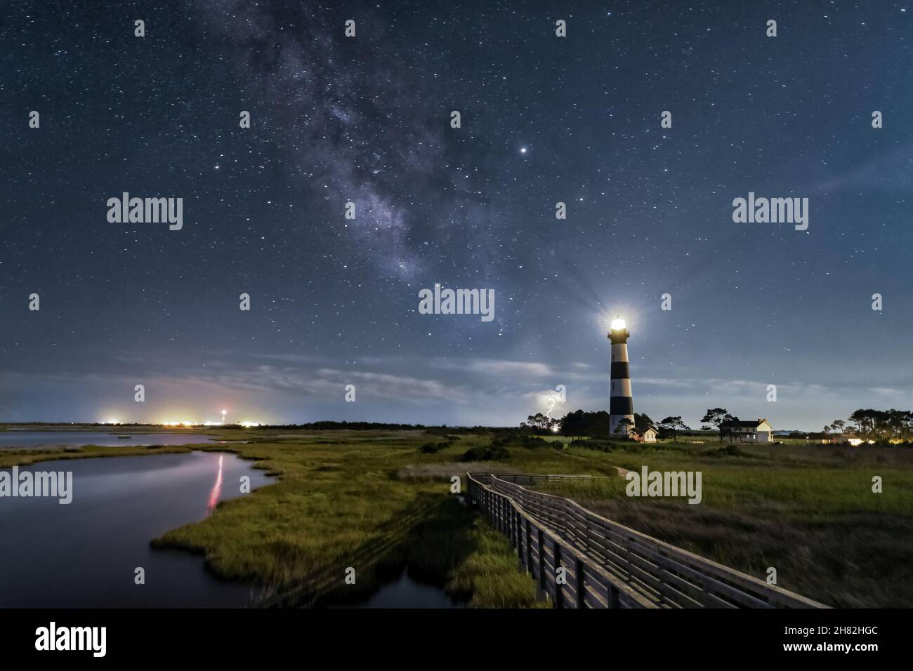 Beautiful coastal landscape with a lighthouse under a starry night sky ...