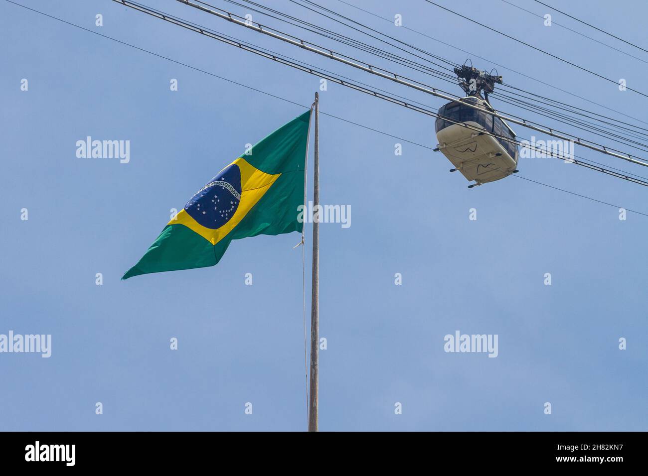 brazilian flag with Sugarloaf cable car in Rio de Janeiro, Brazil - October 23, 2021: brazil flag with sugarloaf cable car in the background in Rio de Stock Photo