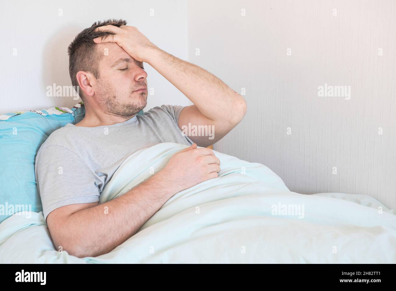 Illness man on bed and holding her head. Near lying napkins and