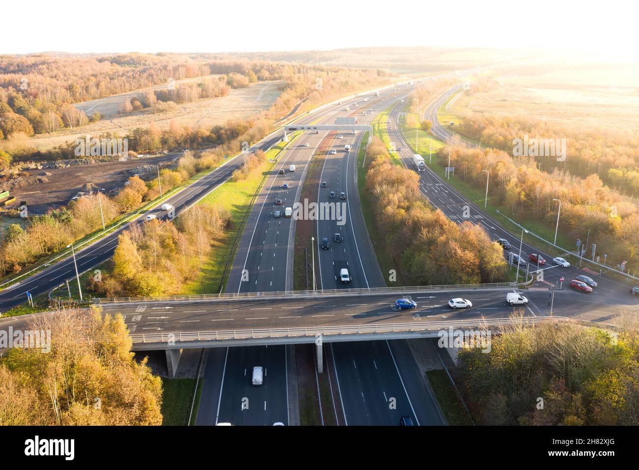 Aerial landscape view of a UK Motorway and overpass bridge through picturesque countryside at sunset Stock Photo