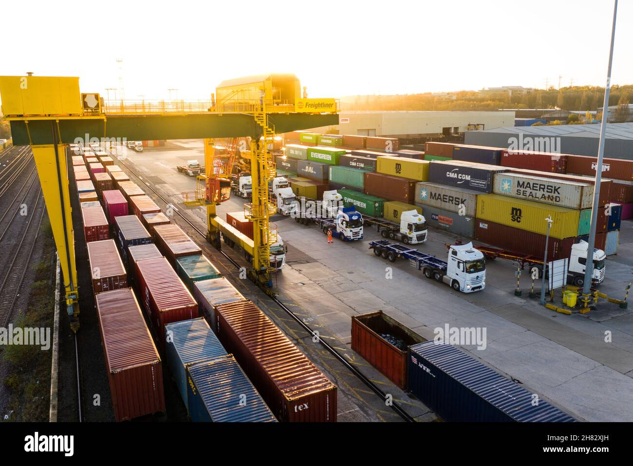Aerial view of a busy shipping container rail terminal in Leeds with shipping boxes waiting to be loaded onto queuing road and rail cargo transport Stock Photo