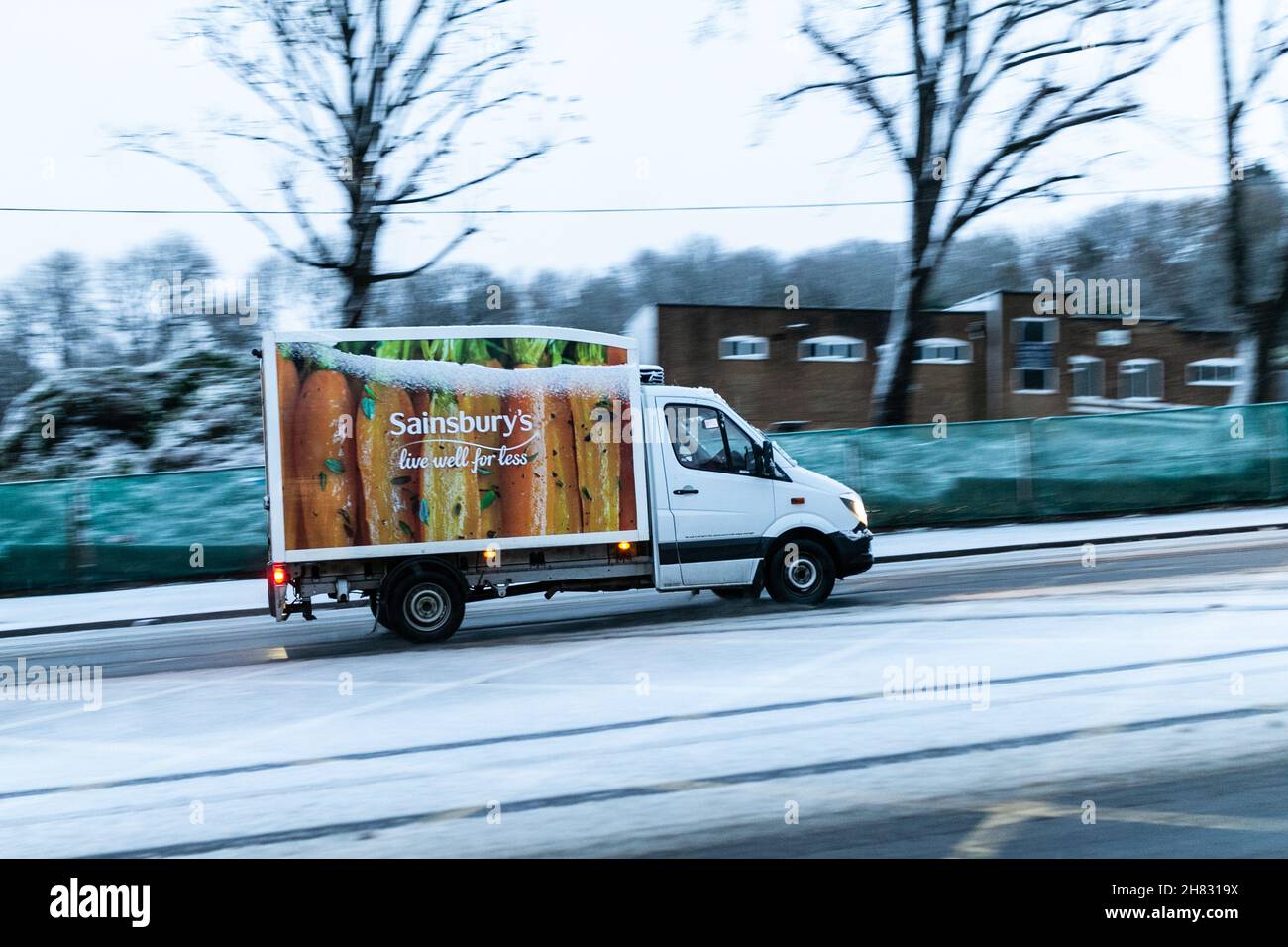 Cradley Heath, West Midlands, UK. 27th Nov, 2021. A Sainbury's delivery van makes its way up a hill as a blanket of snow hits the the roads in Cradley Heath, West Midlands, as Saturday morning traffic is thanksfully light. Road conditions are dangerous. Credit: Peter Lopeman/Alamy Live News Stock Photo