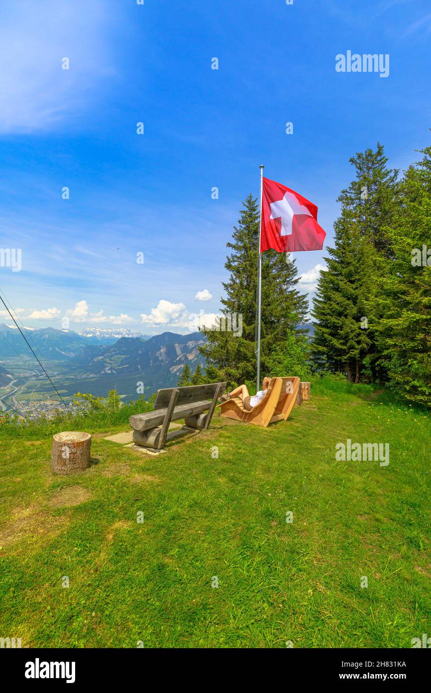 Woman relaxing in Brambruesch of Switzerland. Swiss cable car of Chur town  with Swiss flag. Chur skyline in Grisons canton. Red cable car cabin from  Stock Photo - Alamy