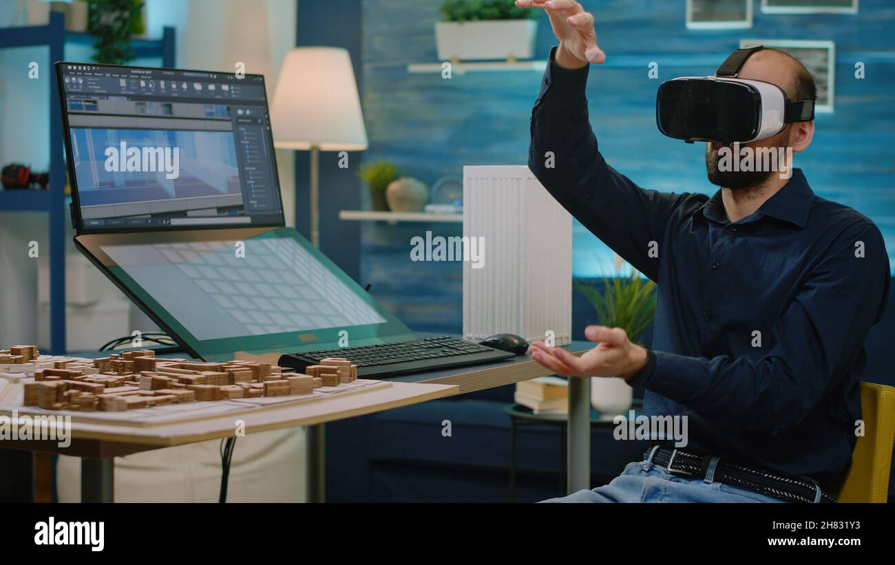 Man engineer working with vr glasses to design building model for architectural development. Architect using digital goggles and creating construction layout. Virtual architecture Stock Photo